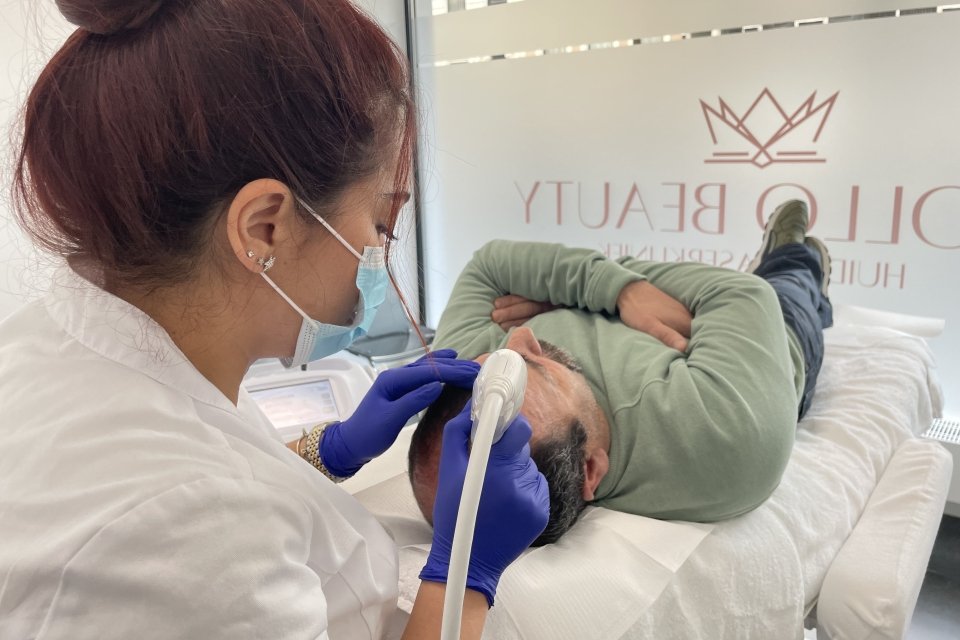 Huidtherapeut voert Mesotherapie behandeling haargroei uit bij mannelijke cliënt.