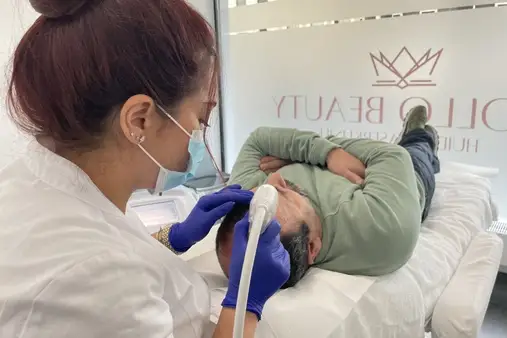 Huidtherapeut voert Mesotherapie behandeling haargroei uit bij mannelijke cliënt.