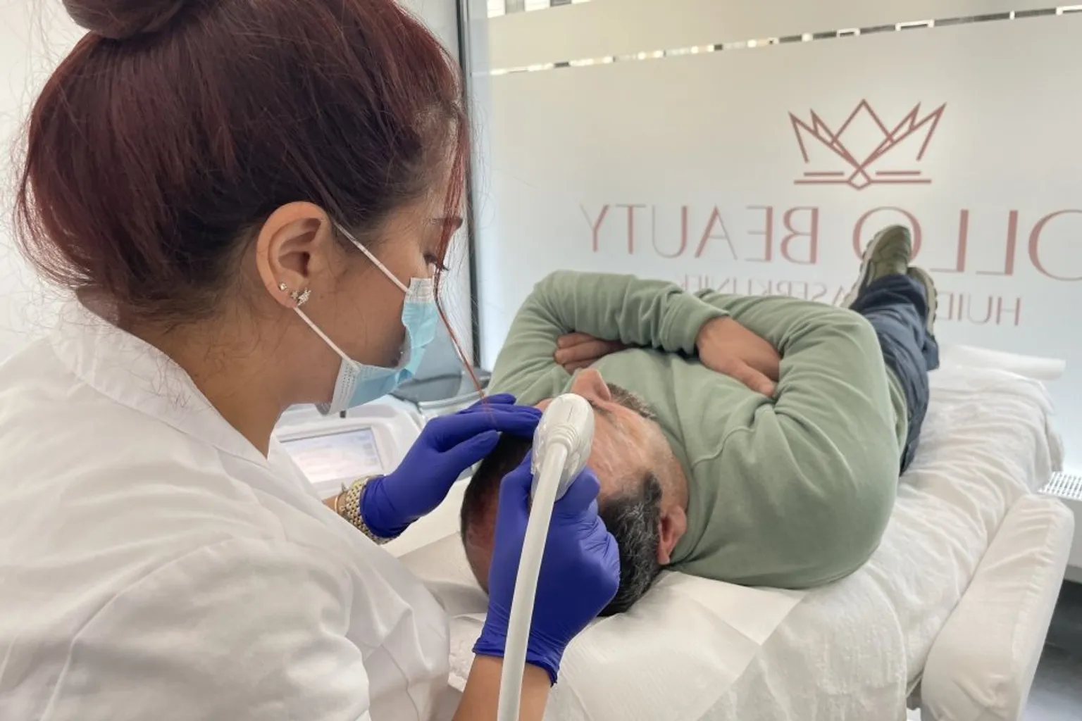 Huidtherapeut voert Mesotherapie behandeling haargroei uit bij mannelijke cliënt.